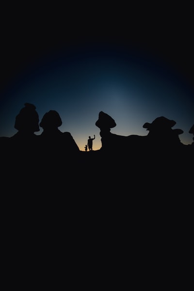 在夜间轮廓的人站在山上

